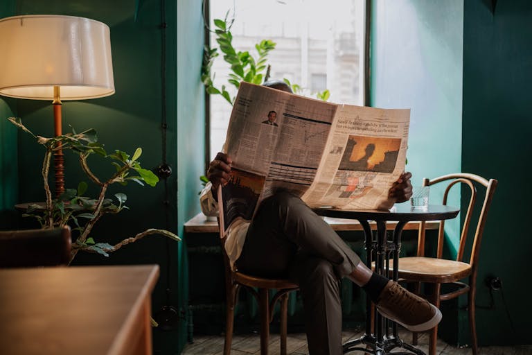 A man sits in a cozy café corner, enjoying a newspaper and relaxed ambiance.